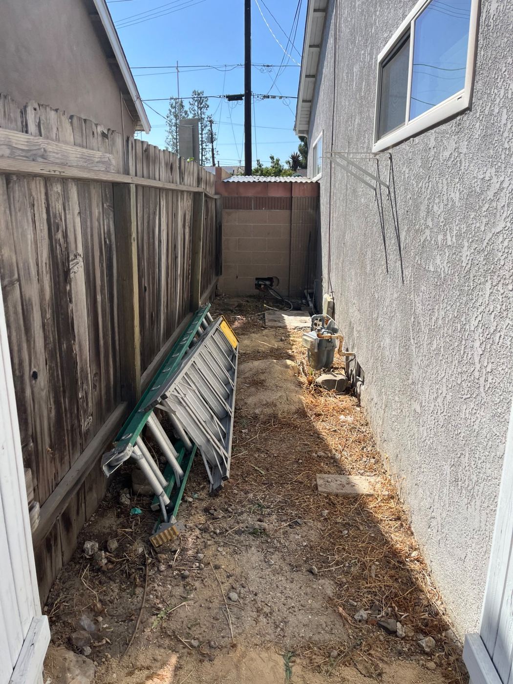 Narrow side yard with an old ladder and bins ready for Blackstone Junk Removal pickup
