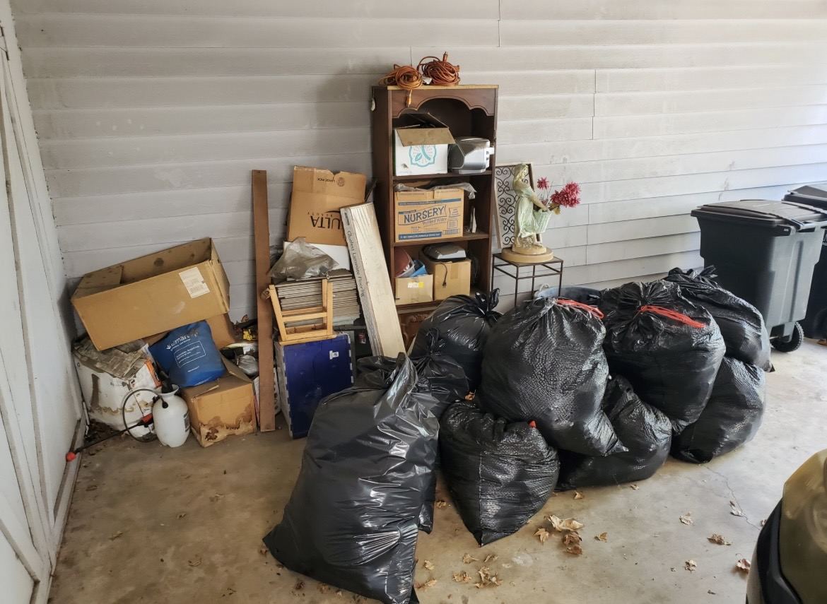 Garage corner staged with bagged junk and boxes ready for Blackstone Junk Removal pickup
